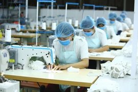 Công nhân Công ty Cổ phần Thời trang K’s Closet (Hà Nội) sản xuất khẩu trang kháng khuẩn. (Ảnh: Anh Tuấn/TTXVN)