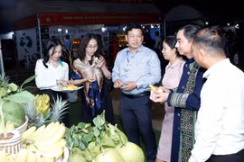 Các quan khách và người dân địa phương ăn thử các loại hoa quả do một doanh nghiệp Việt Nam trồng tại khu vực Tam giác Phát triển CLV. (Ảnh: Phạm Kiên/TTXVN)