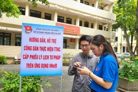Đoàn viên thanh niên Sở Tư pháp hướng dẫn công dân thực hiện cấp Phiếu Lý lịch tư pháp trên VNeID. (Ảnh: Kim Anh/TTXVN)