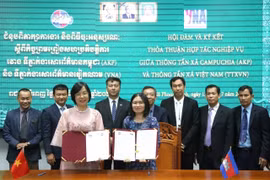 Tổng Giám đốc TTXVN Vũ Việt Trang (bên trái) và Tổng Giám đốc AKP Sokmom Nimul trao đổi thỏa thuận hợp tác nghiệp vụ giai đoạn mới vừa ký kết. (Ảnh: Hoàng Minh/TTXVN)