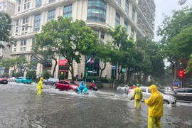 Lực lượng chức năng ứng trực tiêu thoát nước trên đường Lý Thường Kiệt, quận Hoàn Kiếm. (Ảnh: TTXVN phát)