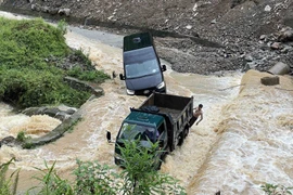 Nước lũ chảy xiết khiến một chiếc xe gặp nạn trên đường qua xã Pả Vi, huyện Mèo Vạc. (Ảnh: Trần Việt/TTXVN)