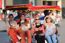 Du khách quốc tế trên xe xích lô đi tham quan Phố cổ, Hồ Hoàn Kiếm. (Ảnh: Thanh Tùng/TTXVN)