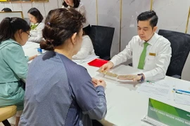Khách hàng mua vàng miếng thực hiện giao dịch tại Ngân hàng Vietcombank ở Thành phố Hồ Chí Minh. (Ảnh: Thanh Vũ/TTXVN)