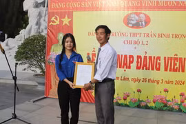 Đại diện Đảng ủy Trường Trung học Phổ thông Trần Bình Trọng, huyện Cam Lâm trao Quyết định kết nạp đảng viên cho quần chúng ưu tú Lâm Uyên Kha. (Ảnh: Phan Sáu/TTXVN)