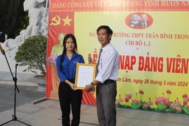 Đại diện Đảng ủy Trường Trung học Phổ thông Trần Bình Trọng, huyện Cam Lâm trao Quyết định kết nạp đảng viên cho quần chúng ưu tú Lâm Uyên Kha. (Ảnh: Phan Sáu/TTXVN)