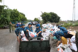Lực lượng chức năng cùng người dân xã Đại Áng (huyện Thanh Trì, Hà Nội) chuẩn bị gần 10.000 bao tải cát, đóng cọc để gia cố đê tả sông Nhuệ đoạn qua Trạm bơm Hòa Bình. (Ảnh: TTXVN phát)
