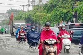 Người dân vượt dòng nước ngập trên đường Kha Vạn Cân (thành phố Thủ Đức). (Ảnh: Hồng Giang/TTXVN)