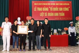 Đại diện Chỉ huy Lữ đoàn 682 (ngoài cùng bên trái) trao Bằng 'Tổ quốc ghi công' cho gia đình Liệt sỹ Đoàn Anh Tuấn. (Ảnh: TTXVN phát)