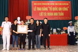Đại diện Chỉ huy Lữ đoàn 682 (ngoài cùng bên trái) trao Bằng 'Tổ quốc ghi công' cho gia đình Liệt sỹ Đoàn Anh Tuấn. (Ảnh: TTXVN phát)