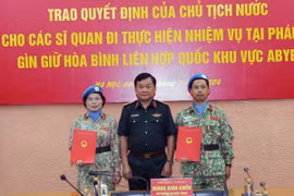 Thượng tướng Hoàng Xuân Chiến, Thứ trưởng Quốc phòng, Tổ trưởng Tổ Công tác liên ngành, Trưởng Ban Chỉ đạo Bộ Quốc phòng về tham gia hoạt động gìn giữ hòa bình Liên hợp quốc trao Quyết định của Chủ tịch nước cho thượng tá Nguyễn Thị Liên và trung tá Nguyễn Đức Doanh. (Ảnh: Trọng Đức/TTXVN)