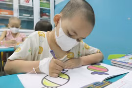 Bệnh nhi đi học với bàn tay còn gắn kim tiêm, dịch truyền. (Ảnh: Đinh Hằng/TTXVN)