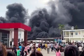 Ban đầu đám cháy nhỏ, sau đó lan rộng ra cả nhà để xe, khói đen bốc lên cao hàng chục mét. (Ảnh: TTXVN phát)