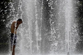 Người dân làm mát tại một đài phun nước ở Seville, Tây Ban Nha. (Ảnh: AFP/TTXVN)