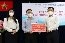 Ông Phạm Minh Tuấn, Phó Chủ tịch Ủy ban MTTQ Việt Nam Thành phố Hồ Chí Minh (giữa) tiếp nhận tượng trưng kinh phí ủng hộ công tác phòng, chống dịch từ Tổng Công ty Điện lực Thành phố Hồ Chí Minh. (Ảnh: Xuân Khu/TTXVN)