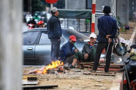 Người lao động đốt củi sưởi ấm khi nhiệt độ xuống thấp. (Ảnh: Thành Đạt/TTXVN)