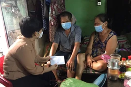 Bà Trương Minh Kiều, quyền Chủ tịch UBND quận 5, tặng quà và trao hỗ trợ cho hộ gia đình nghèo ông Đoàn Văn Bội, ngụ tại phường 8, quận 5, làm nghề chạy xe ôm truyền thống. (Ảnh: Thanh Vũ/TTXVN)