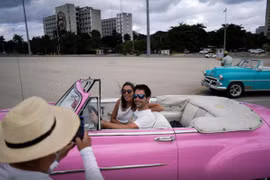 Du khách nước ngoài chụp ảnh với xe cổ tại thủ đô La Havana, Cuba. (Nguồn: Reuters)