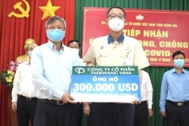Chủ tịch UBND tỉnh Đồng Nai Cao Tiến Dũng (trái) tiếp nhận 300.000 USD từ Đại diện Công ty cổ phần Taekwang Vina ủng hộ Quỹ vaccine phòng, chống dịch COVID-19. (Ảnh: TTXVN phát)
