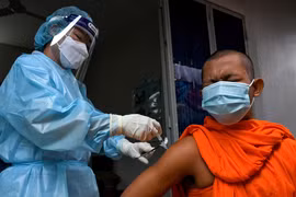 Nhân viên y tế tiêm vaccine ngừa COVID-19 cho nhà sư tại Phnom Penh, Campuchia. Trẻ em dưới 5 tuổi chưa được tiêm vaccine. (Ảnh: AFP/TTXVN)