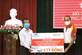 Đại diện Tập đoàn Sovico và Ngân hàng Thương mại Cổ phần Phát triển Thành phố Hồ Chí Minh HDBank (phải) trao bảng tượng trưng tăng tỉnh An Giang 1 xe cấp cứu, 5 máy thở cao cấp, 2.500 bộ quần áo bảo hộ y tế. (Ảnh: Công Mạo/TTXVN)