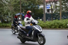Người dân khi ra đường nên mặc ấm, đeo khẩu trang và mang theo áo mưa đề phòng những cơn mưa. (Ảnh: Tuấn Đức/TTXVN)