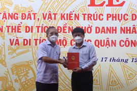 Ông Trần Đức Nghị, Trưởng gia tộc Trần Đức, trao sổ đỏ 1.800m2 đất cho đại diện lãnh đạo thị xã Hoài Nhơn. (Ảnh: Phạm Kha/TTXVN)