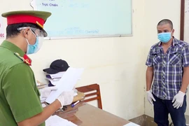 Lực lượng chức năng đọc lệnh bắt tạm giam đối với Nguyễn Ngọc Sơn. (Ảnh: TTXVN phát)