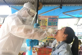 Lấy mẫu xét nghiệm COVID-19 của những người làm việc tại bến xe Bình Dương. (Ảnh: Văn Hướng/TTXVN)