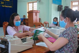 Người dân phường Quyết Thắng, thành phố Kon Tum làm thủ tục nhận tiền vay vốn tín dụng chính sách. (Ảnh: Dư Toán/TTXVN)
