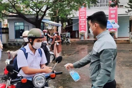 Học sinh trường THPT Hoàng Hoa Thám xịt sát khuẩn tay tại cổng trường. (Ảnh: Văn Dũng/TTXVN)