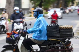 Nhiều người phải mặc áo mưa ra đường vì gió lạnh. (Ảnh: Tuấn Đức/TTXVN)