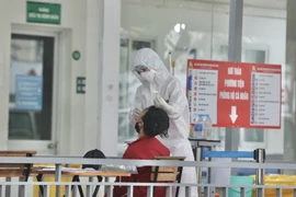 Nhân viên y tế bệnh viện Thanh Nhàn lấy mẫu xét nghiệm COVID-19 cho người đến khám có triệu chứng. (Ảnh: Minh Quyết/TTXVN)