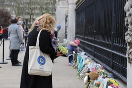 Người dân London đến đặt hoa tưởng niệm Hoàng thân Philip dọc theo cổng của Cung điện Buckingham. (Ảnh: Hải Vân/TTXVN)