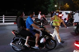 Tổ công tác Y12/141 dừng xe và kiểm tra trường hợp không đội mũ bảo hiểm khi tham gia giao thông. (Ảnh: Phạm Kiên/TTXVN)