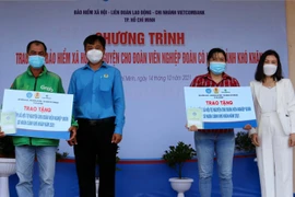  Lãnh đạo Liên đoàn Lao động quận Tân Phú, TP Hồ Chí Minh trao sổ bảo hiểm cho đoàn viên nghiệp đoàn có hoàn cảnh khó khăn. (Ảnh: Thanh Vũ/TTXVN)