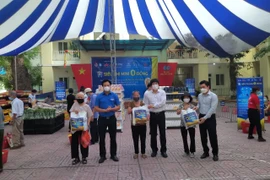 Lãnh đạo UBND quận Đống Đa cùng nhà hảo tâm trao quà "Siêu thị mini 0 đồng" cho người dân gặp khó khăn do dịch COVID-19. (Ảnh TTXVN phát)