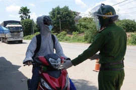 Người từ các tỉnh phía Nam đi xe môtô về quê được Công an thành phố Đà Nẵng hướng dẫn, đảm bảo an toàn khi đi qua địa bàn thành phố. (Ảnh: Quốc Dũng/TTXVN)