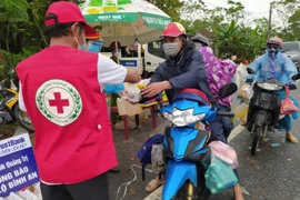 Trao tặng thức ăn và đồ dùng cho những người trở về bằng xe máy từ các tỉnh, thành phía Nam trên Quốc lộ 1A đoạn qua xã Hải Chánh, huyện Hải Lăng, tỉnh Quảng Trị. (Ảnh: Thanh Thủy/TTXVN)