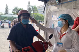 Đo thân nhiệt cho người dân đến khám bệnh tại Bệnh viện Thống Nhất Thành phố Hồ Chí Minh. (Ảnh: Đinh Hằng/TTXVN)