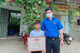 Bí thư Tỉnh đoàn Quảng Bình trao tặng Bằng khen tuyên dương hành động dũng cảm của Mai Hải Đăng. (Ảnh: Võ Dung/TTXVN)