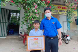 Bí thư Tỉnh đoàn Quảng Bình trao tặng Bằng khen tuyên dương hành động dũng cảm của Mai Hải Đăng. (Ảnh: Võ Dung/TTXVN)