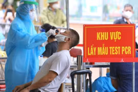 Nhân viên y tế mặc đồ bảo hộ thực hiện xét nghiệm COVID-19 cho người dân tại Hà Nội. (Ảnh: Hoàng Hiếu/TTXVN)