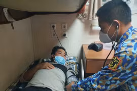 Ngư dân Đặng Văn Tuấn được lực lượng chức năng chăm sóc sức khỏe ban đầu. (Ảnh: TTXVN phát)