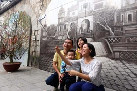 Người dân thủ đô chụp ảnh lưu niệm tại phố Bích họa Phùng Hưng. (Ảnh: Danh Lam/TTXVN)