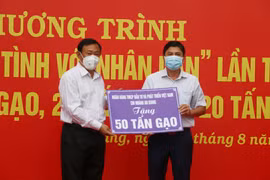 Ông Nguyễn Tiếc Hùng, Chủ tịch Ủy ban Mặt trận Tổ quốc Việt Nam tỉnh An Giang (trái), tiếp nhận bằng tượng trưng hỗ trợ từ các nhà hảo tâm. (Ảnh: Công Mạo/TTXVN)