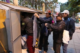 Người dân lao động đến lấy quần áo mặc chống rét tại quầy hàng miễn phí trên phố Nguyễn Chí Thanh. (Ảnh: Thành Đạt/TTXVN)