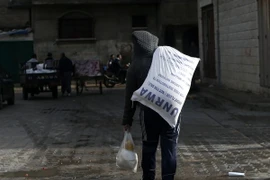 Người dân Palestine chuyển lương thực cứu trợ bên ngoài trung tâm phân phối lương thực của LHQ tại Gaza ngày 15/1. (Nguồn: AFP/TTXVN)
