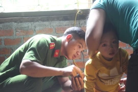 Cơ quan chức năng kiểm tra thân thể cháu Đăng. (Ảnh: Anh Dũng/TTXVN)