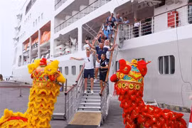 Du khách hào hứng với màn múa lân chào đón khi vừa xuống tàu. (Ảnh: Trần Lê Lâm/TTXVN)